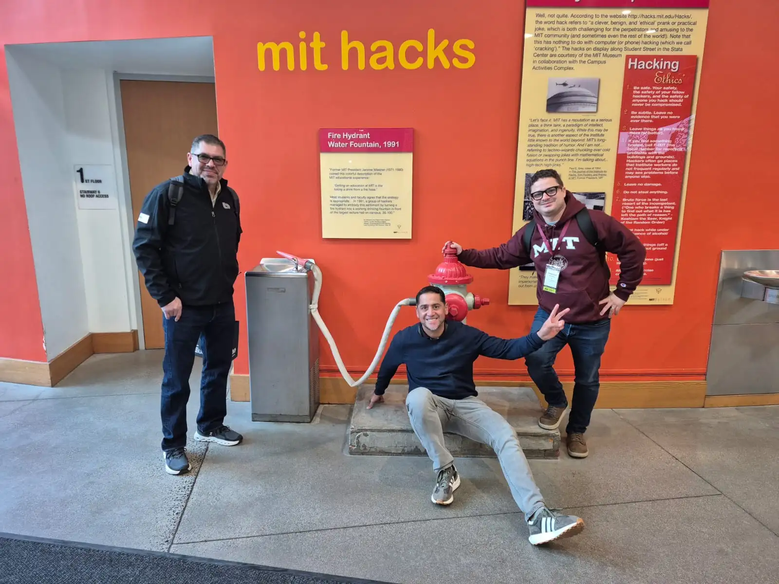 Friends posing with the MIT Fire Hydrant Water Fountain hack exhibit